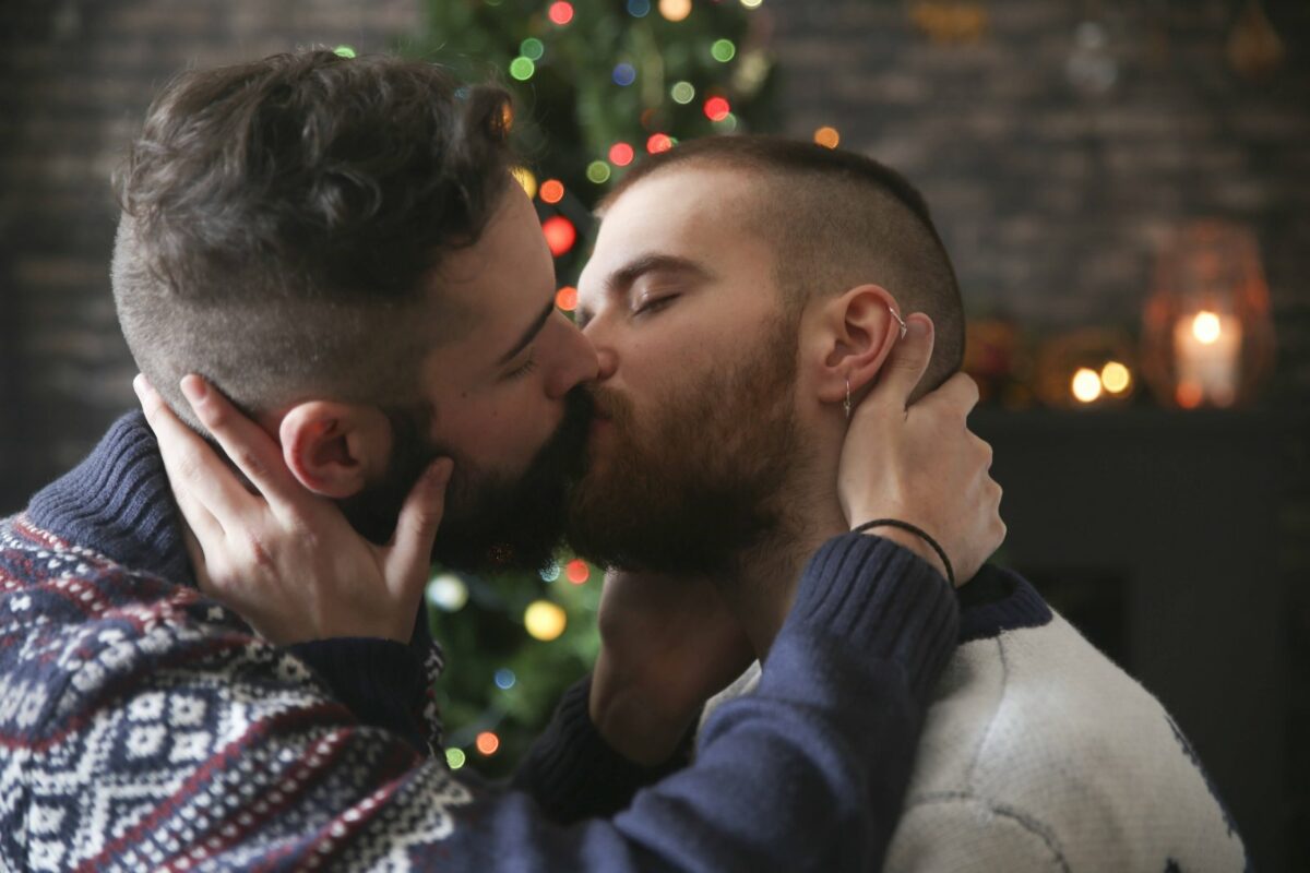 Küssende Männer vor dem Weihnachtsbaum