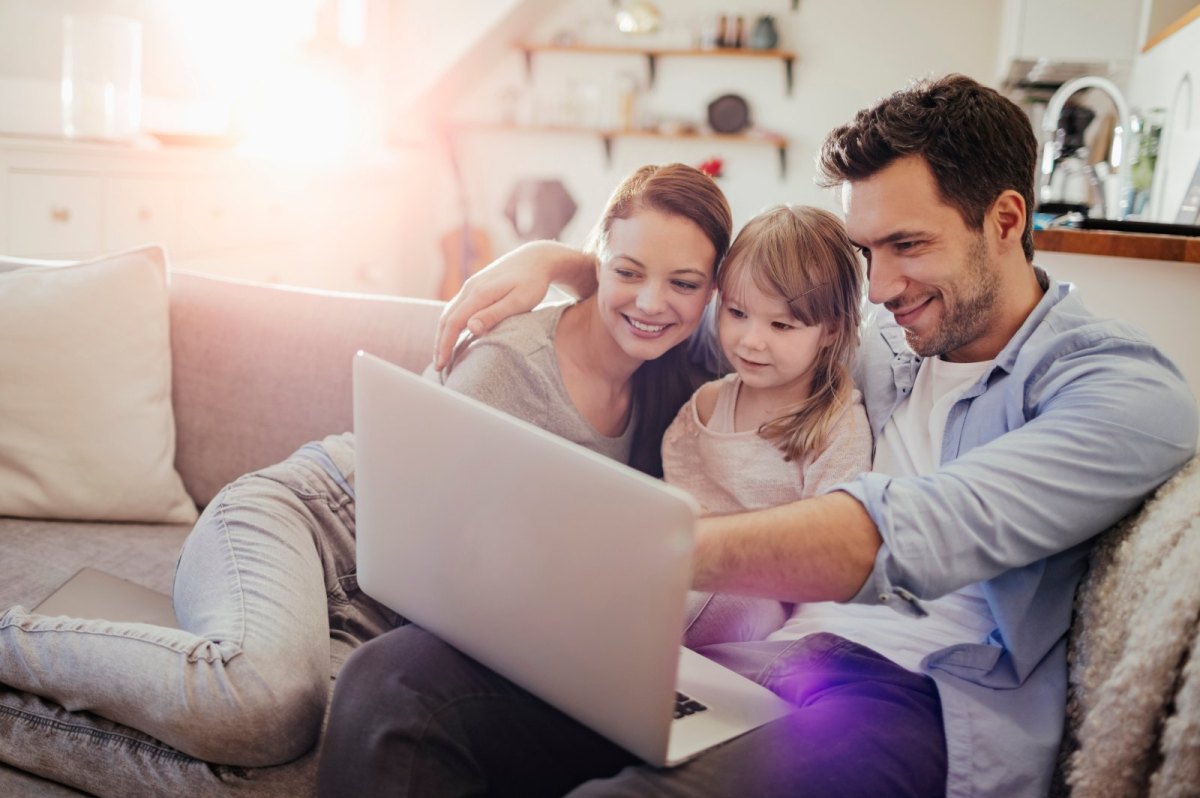 Familie sitzt vor einem Laptop.