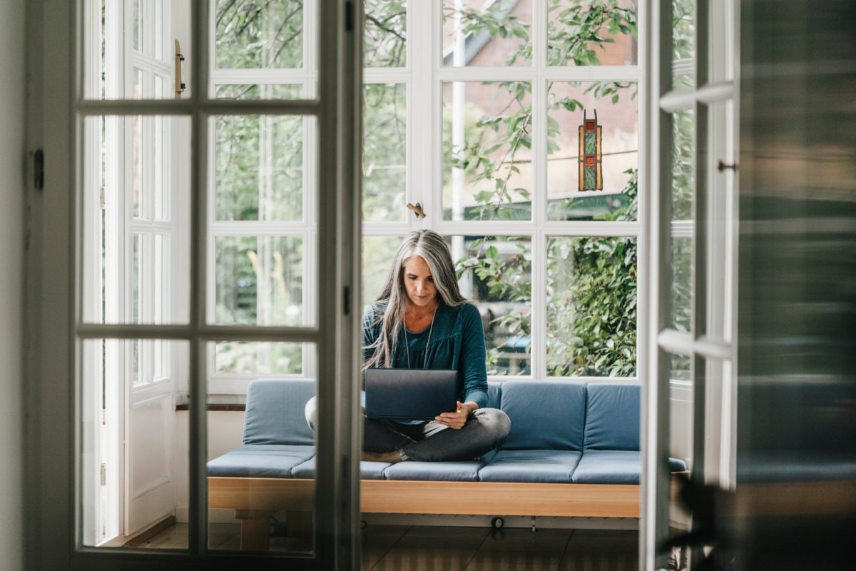 Frau sitzt auf dem Sofa mit Laptop.