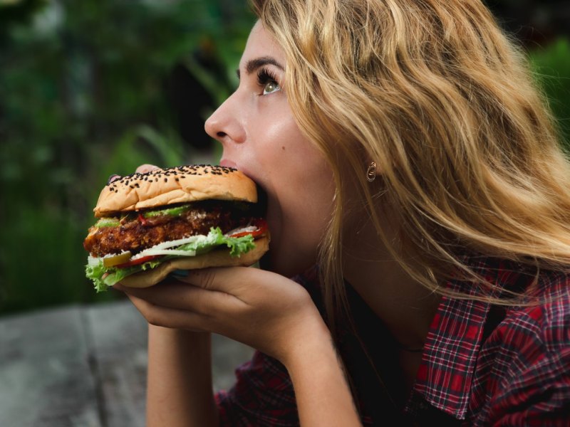 Frau beißt genüsslich in Burger.