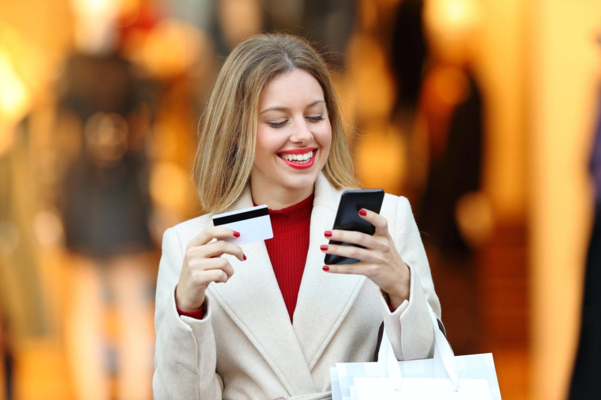 Frau mit Handy und Kreditkarte in der Hand.