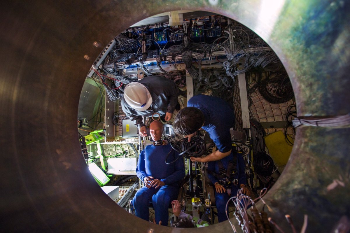 Ein Dummy der NASA wird für seinen Crash-Test in der nachgebildeten Orion-Kapsel vorbereitet.