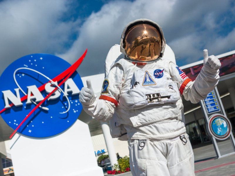Astronaut vor einem Logo der NASA