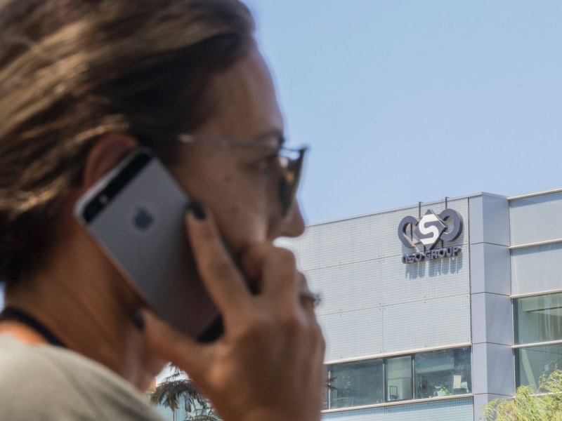 Eine Frau telefoniert mit ihrem iPhone vor dem NSO Gebäude