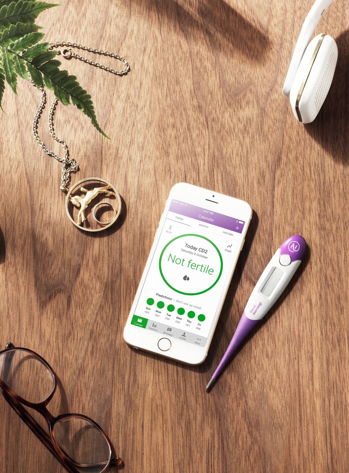 Smartphone mit der App Natural Cycles und einem Thermometer