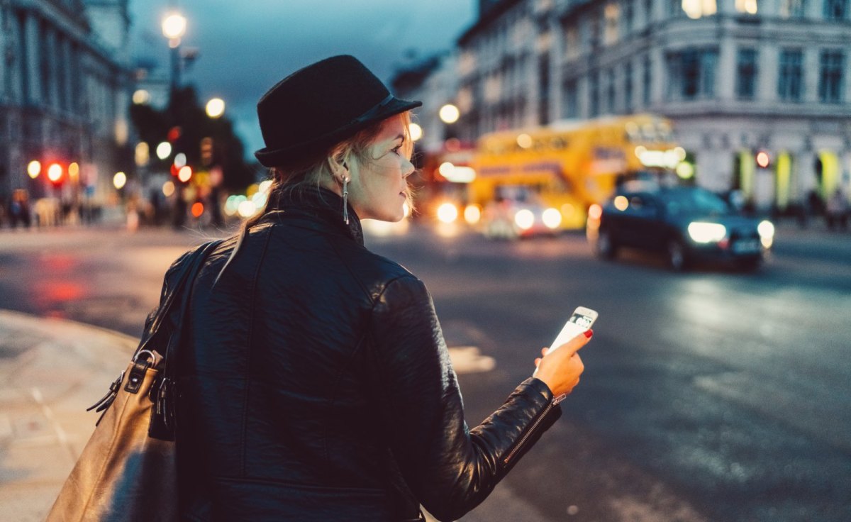 Frau mit Handy schaut sich in der Stadt um.