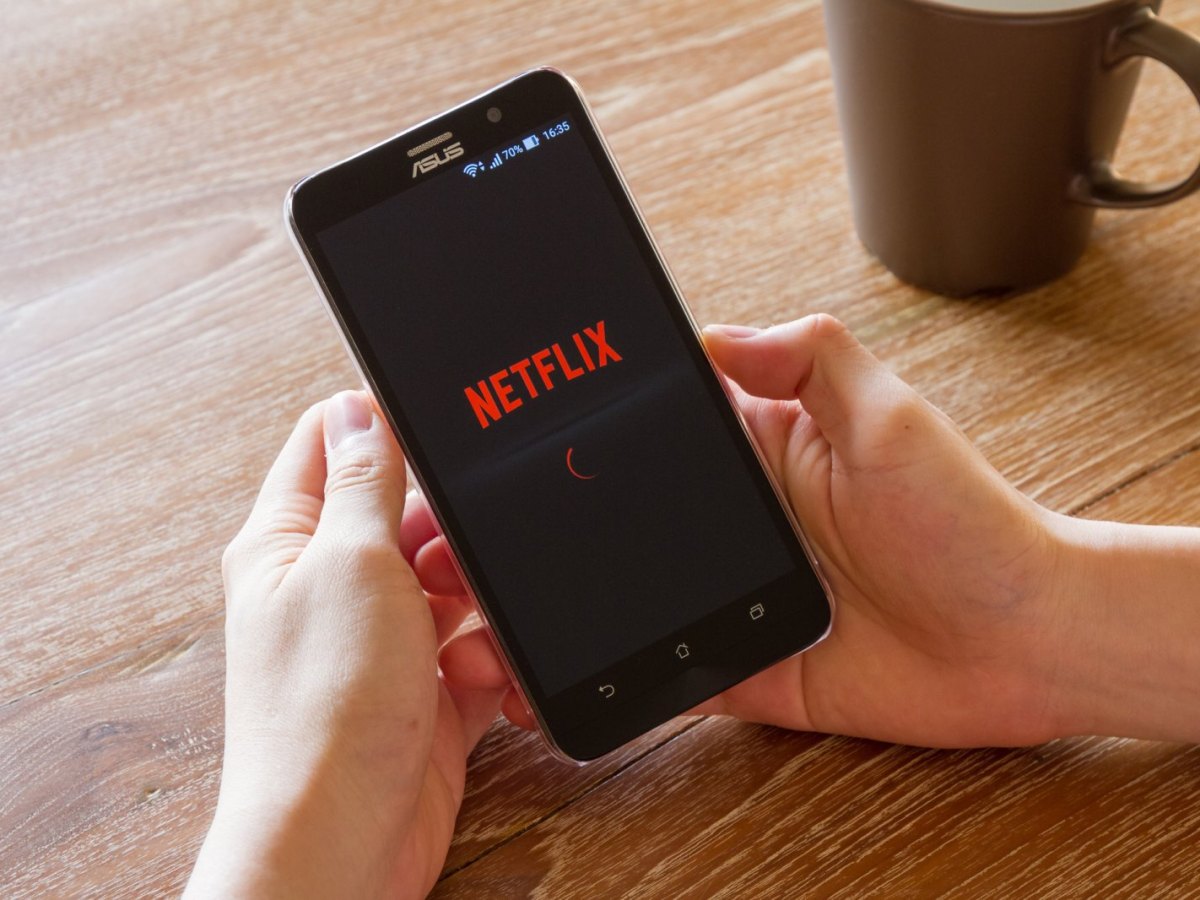 Mensch mit Handy und der Netflix-App