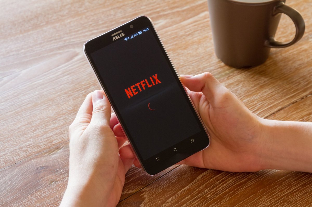 Mensch mit Handy und der Netflix-App