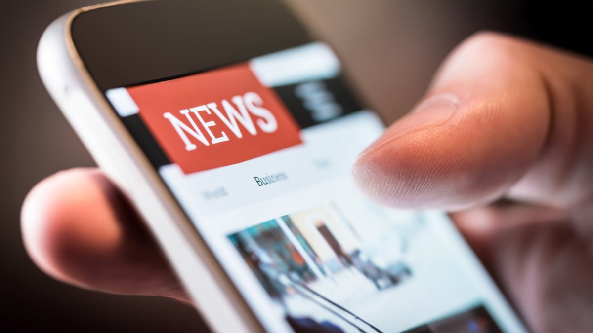 Smartphone mit geöffneter News-App in einer Hand