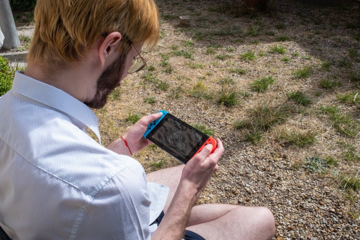 Mann spielt Nintendo Switch im Garten
