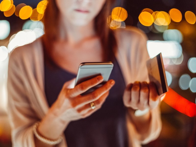 Eine Frau macht Online-Banking per Girocard und Handy.