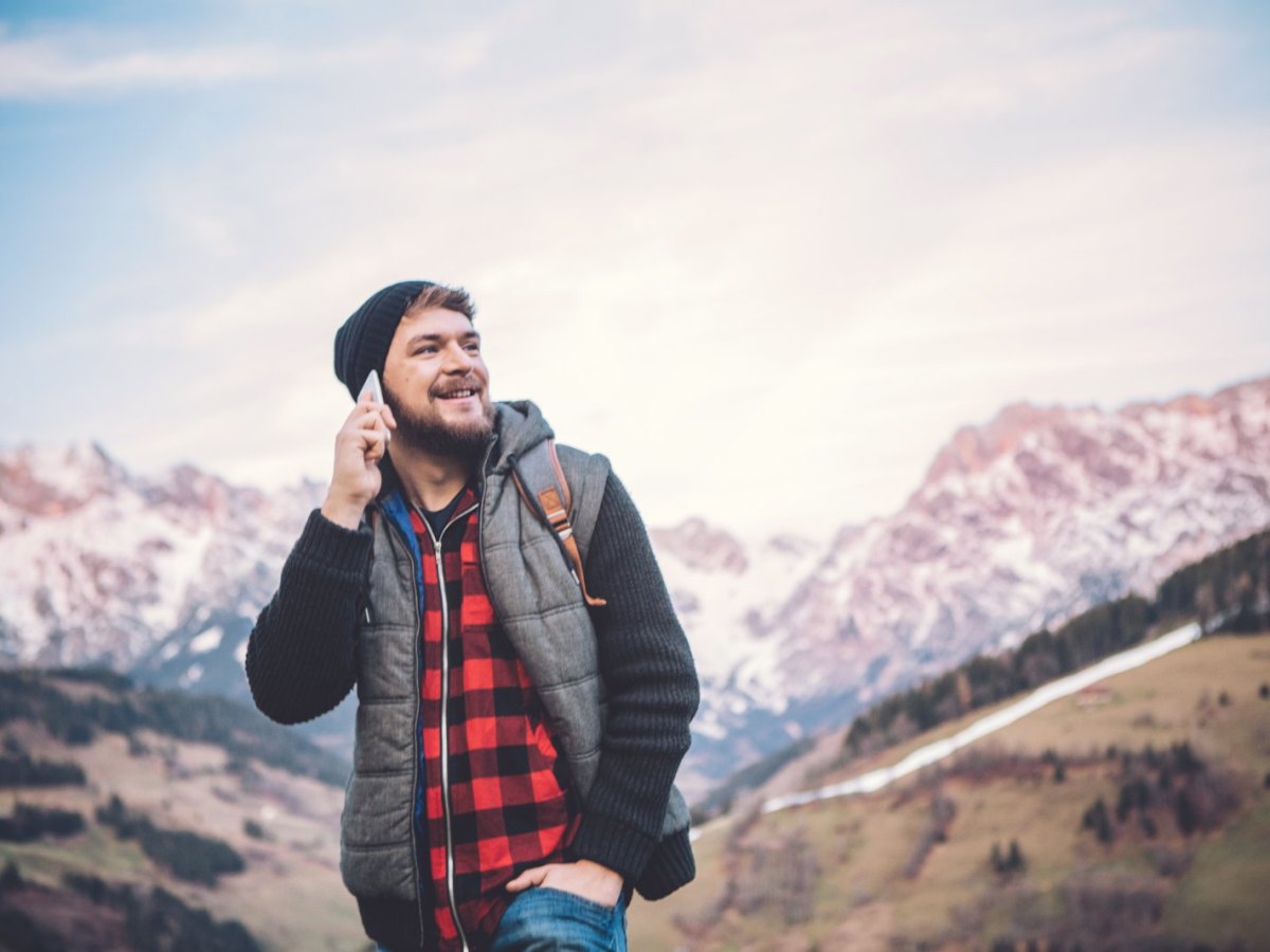 Ein Mann telefoniert mit seinem Handy in den Bergen