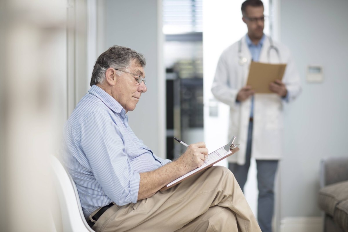 Patient sitzt vor Arztzimmer und füllt Fragebogen aus