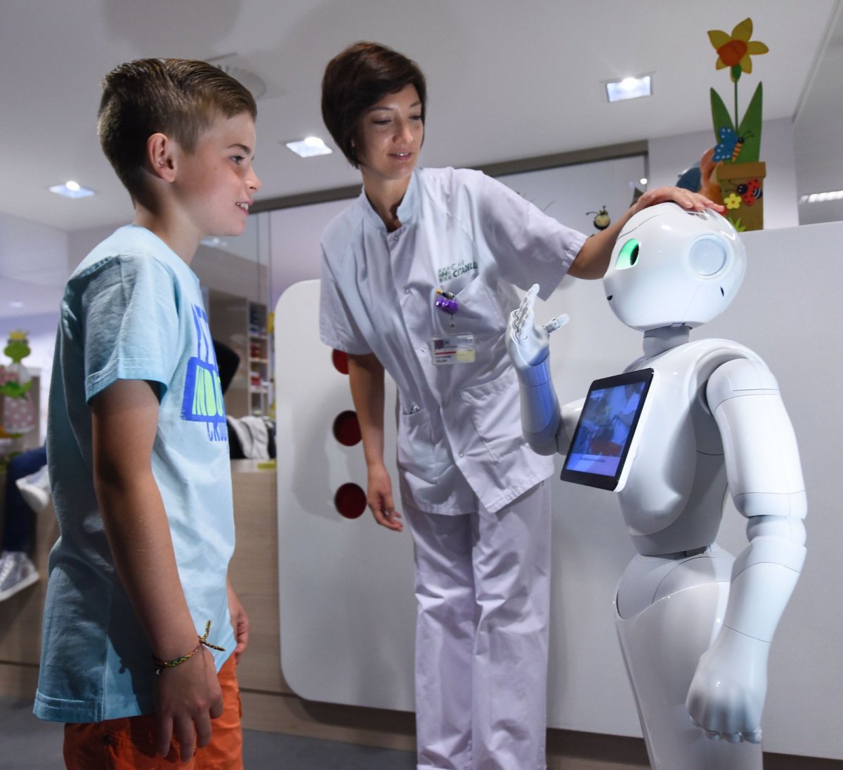 Roboter "Pepper" mit einer Krankenschwester und einem Jungen im Krankenhausflur