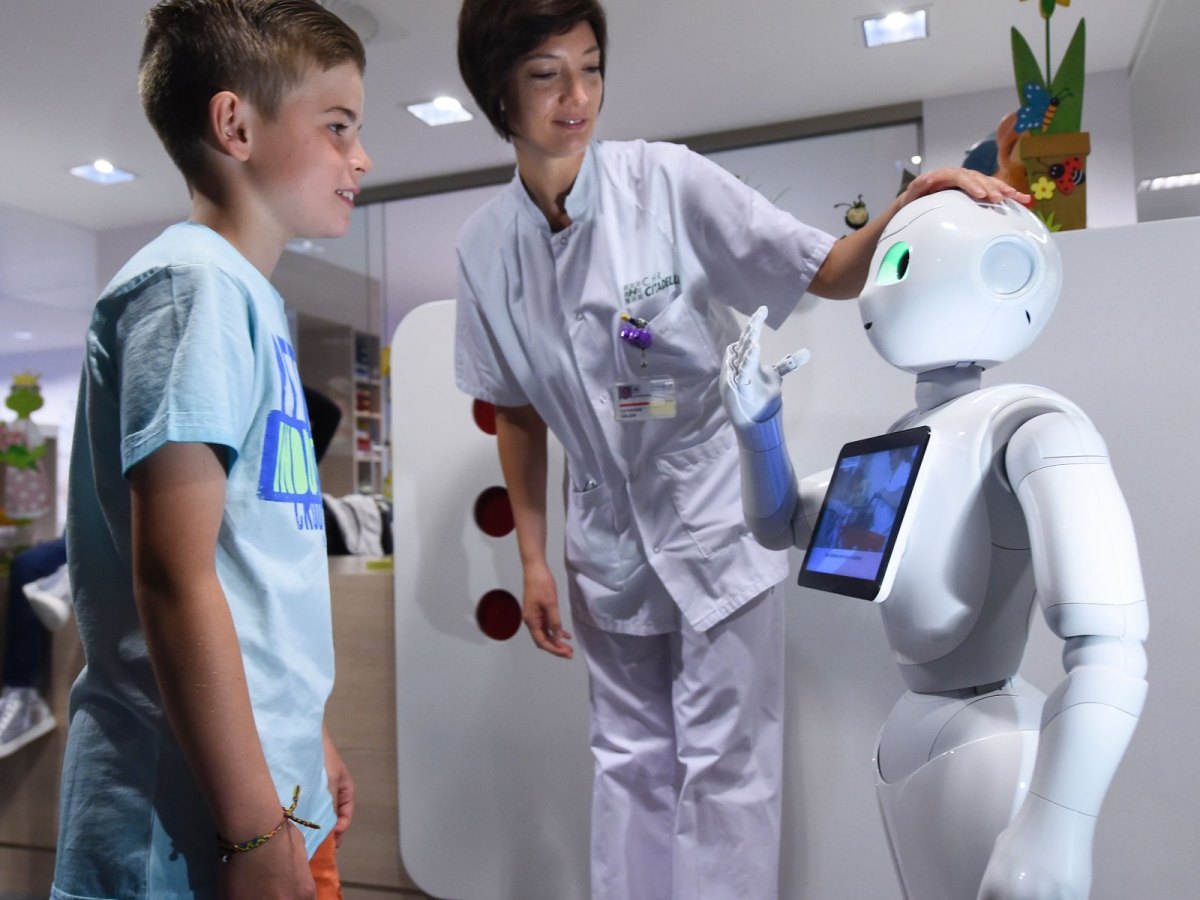 Roboter "Pepper" mit einer Krankenschwester und einem Jungen im Krankenhausflur