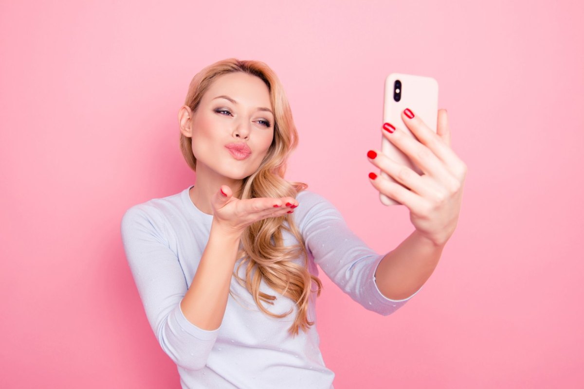 Frau macht Schmollmund und Handkuss für ein Selfie.