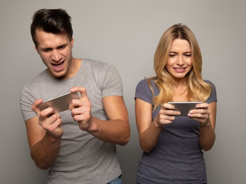 Mann und Frau spielen auf ihren Smartphones Handy-Spiele