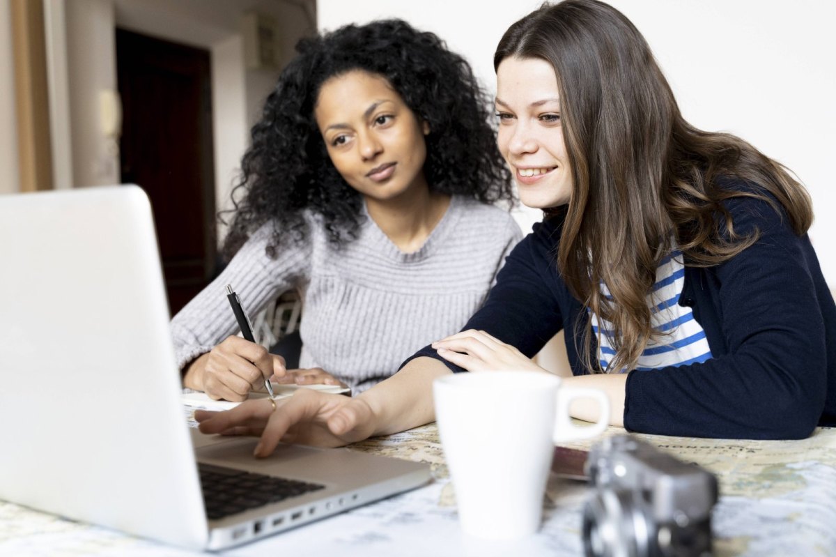 Zwei Frauen bucen eine Reise am Laptop.