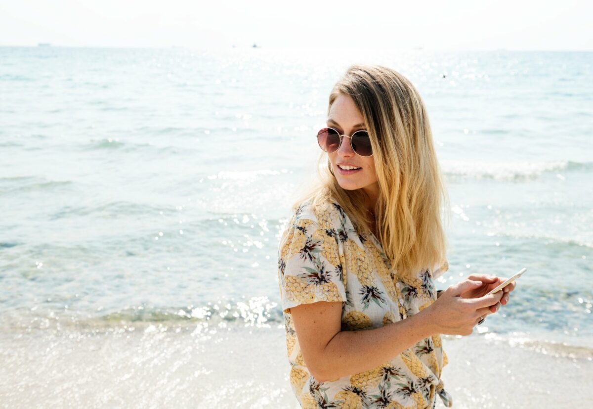 Frau am Strand mit Smartphone