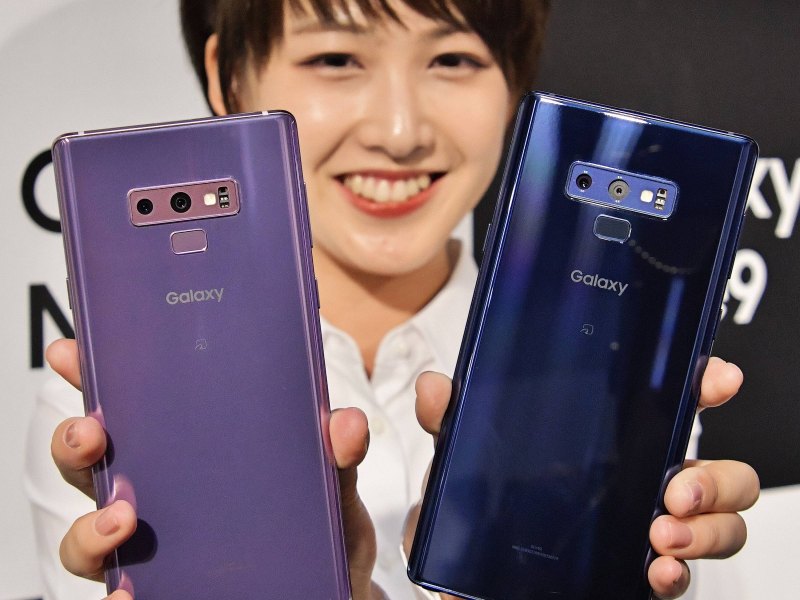 Eine Frau hält zwei Samsung Galaxy Note 9 in die Höhe.