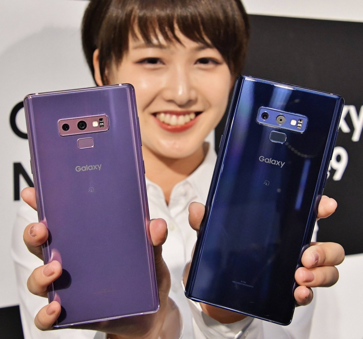 Eine Frau hält zwei Samsung Galaxy Note 9 in die Höhe.