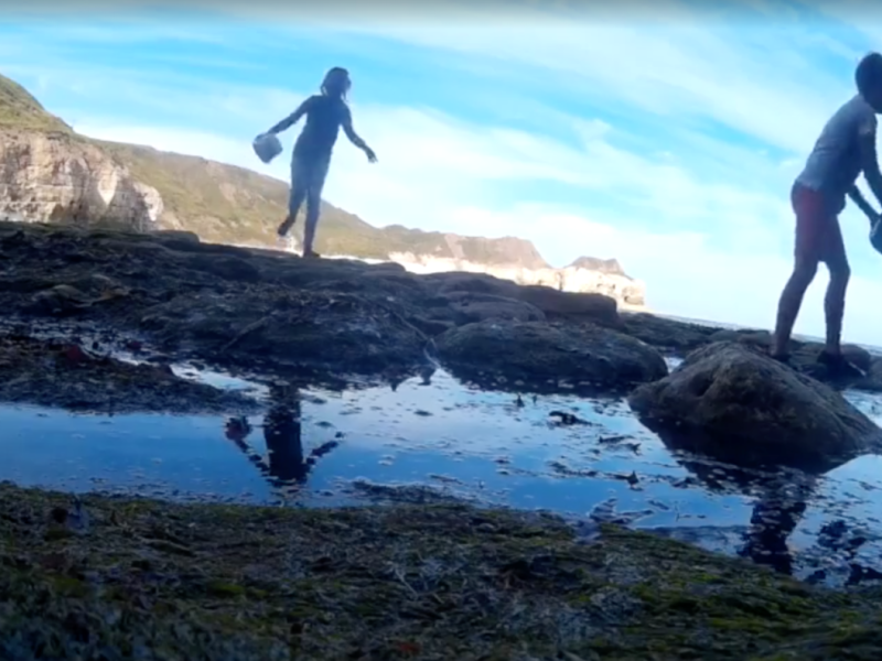 Ein Screenshot aus dem Video zeigt den Jungen und eine Freundin beim Spielen am Strand.