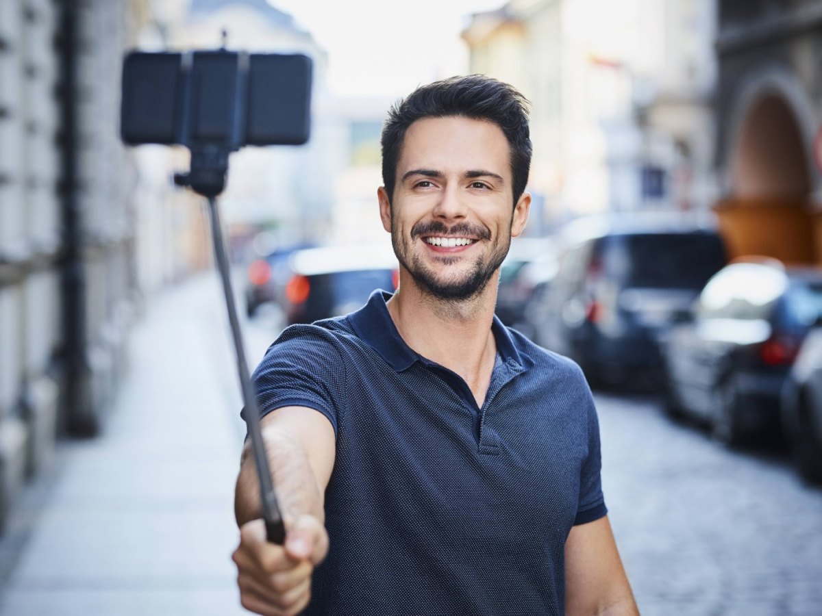 Mann schießt Bild mit Smartphone am Selfie-Stick
