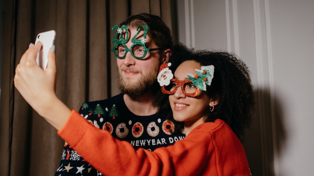 Ein Mann und eine Frau in Silvester-Outfits machen ein Selfie.