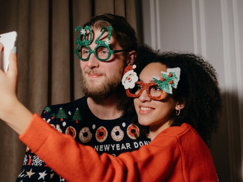 Ein Mann und eine Frau in Silvester-Outfits machen ein Selfie.