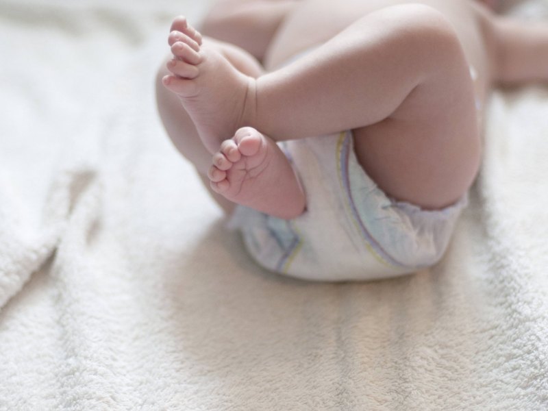 Ein Baby trägt eine Windel und streckt die Füße in die Höhe.