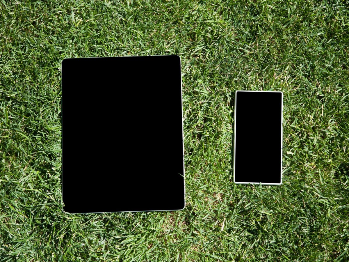Smartphone und Tablet liegen auf Rasen