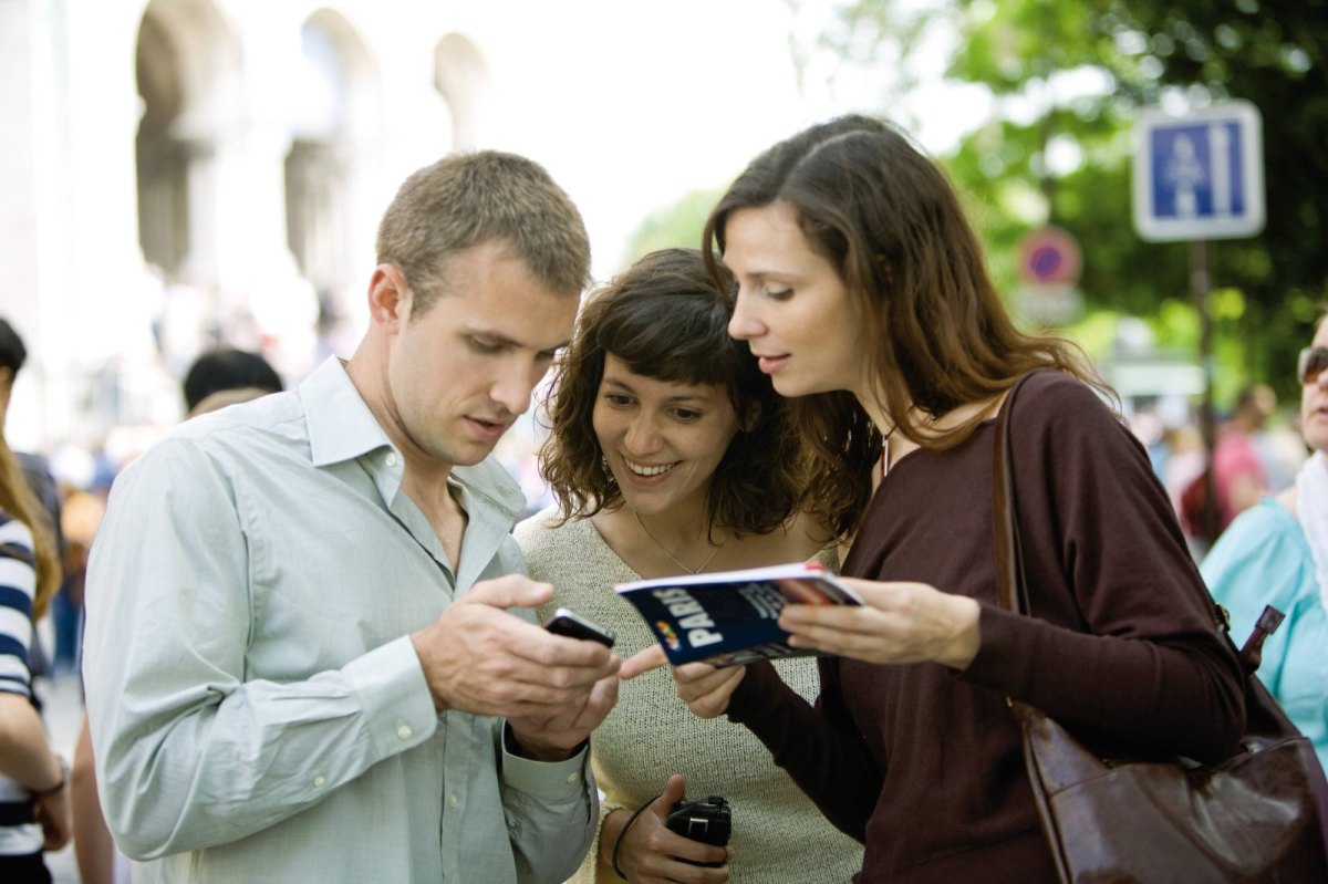 Drei Personen schauen auf ein Smartphone