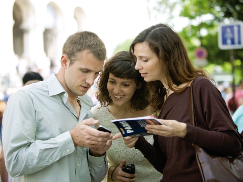 Drei Personen schauen auf ein Smartphone