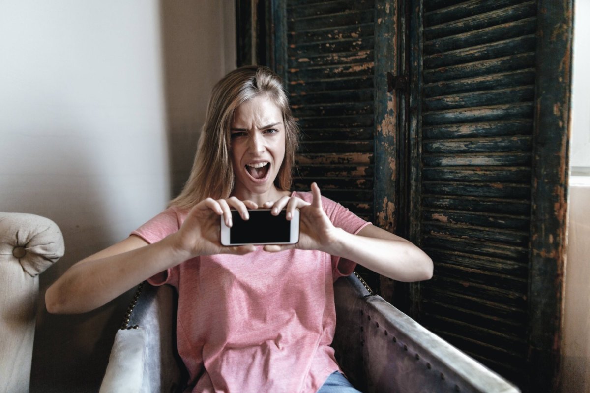 Eine Frau ist wütend und hält ein Smartphone in der Hand.