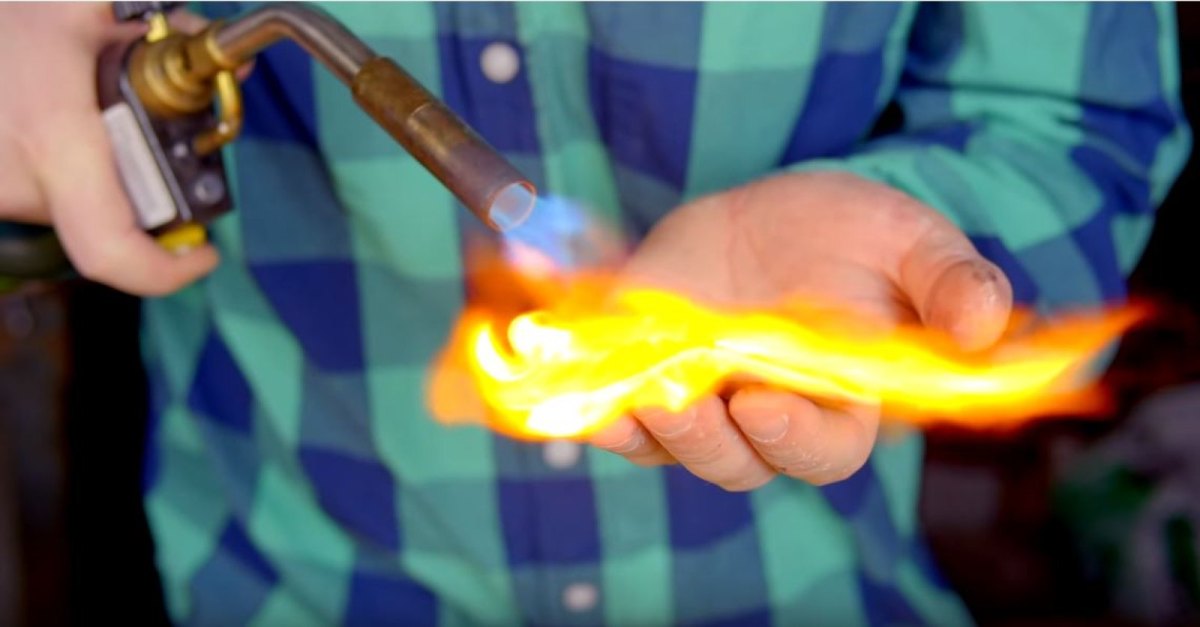 Hobby-Chemiker zündet Material auf seiner bloßen Hand an.