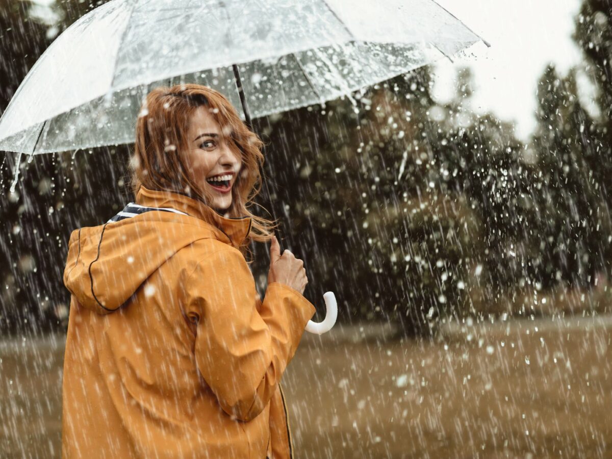 Frau mit Regenschirm geht im Regen spazieren