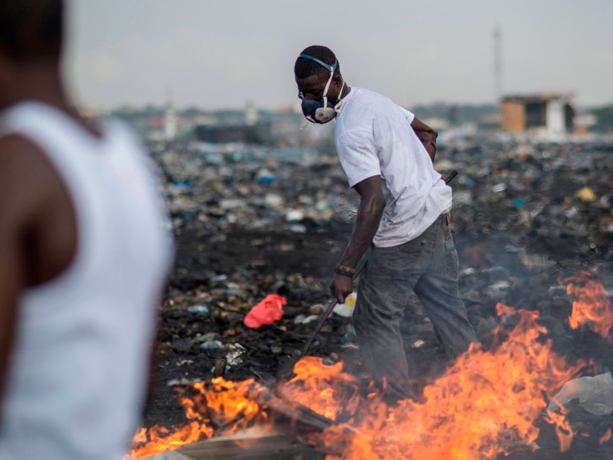 Ein afrikanischer Arbeiter mit Mundschutz auf einer Elektroschrott-Deponie.