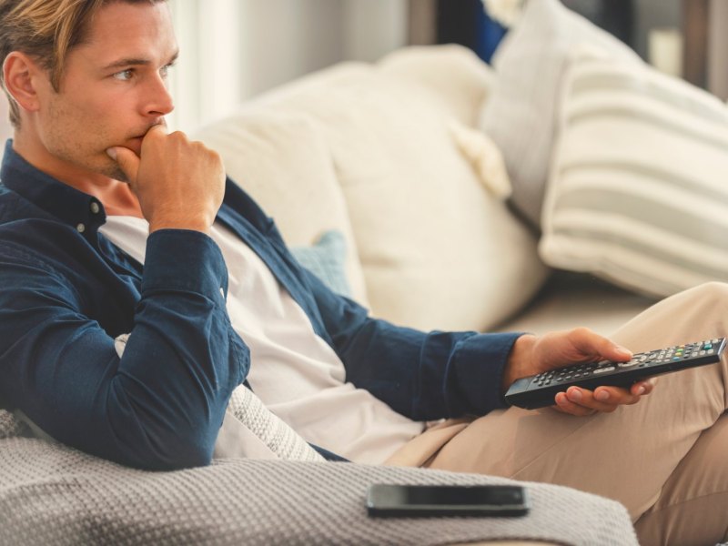 Mann auf dem Sofa mit Fernbedienung