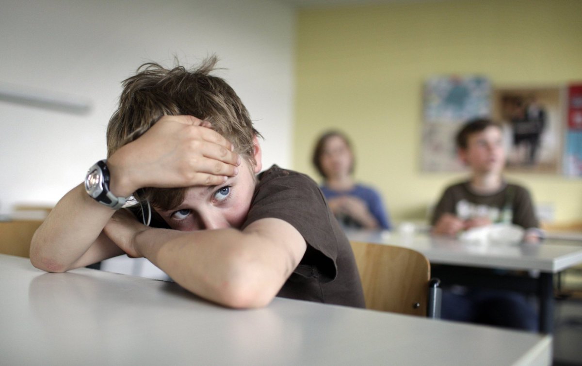 Das Bild zeigt einen traurigen Junge in der Schule