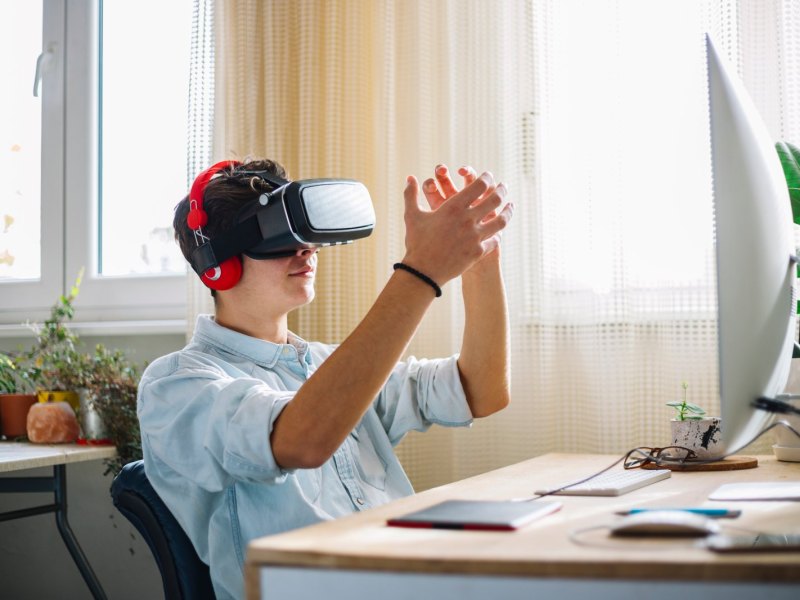 Mann sitzt mit VR Brille vorm PC