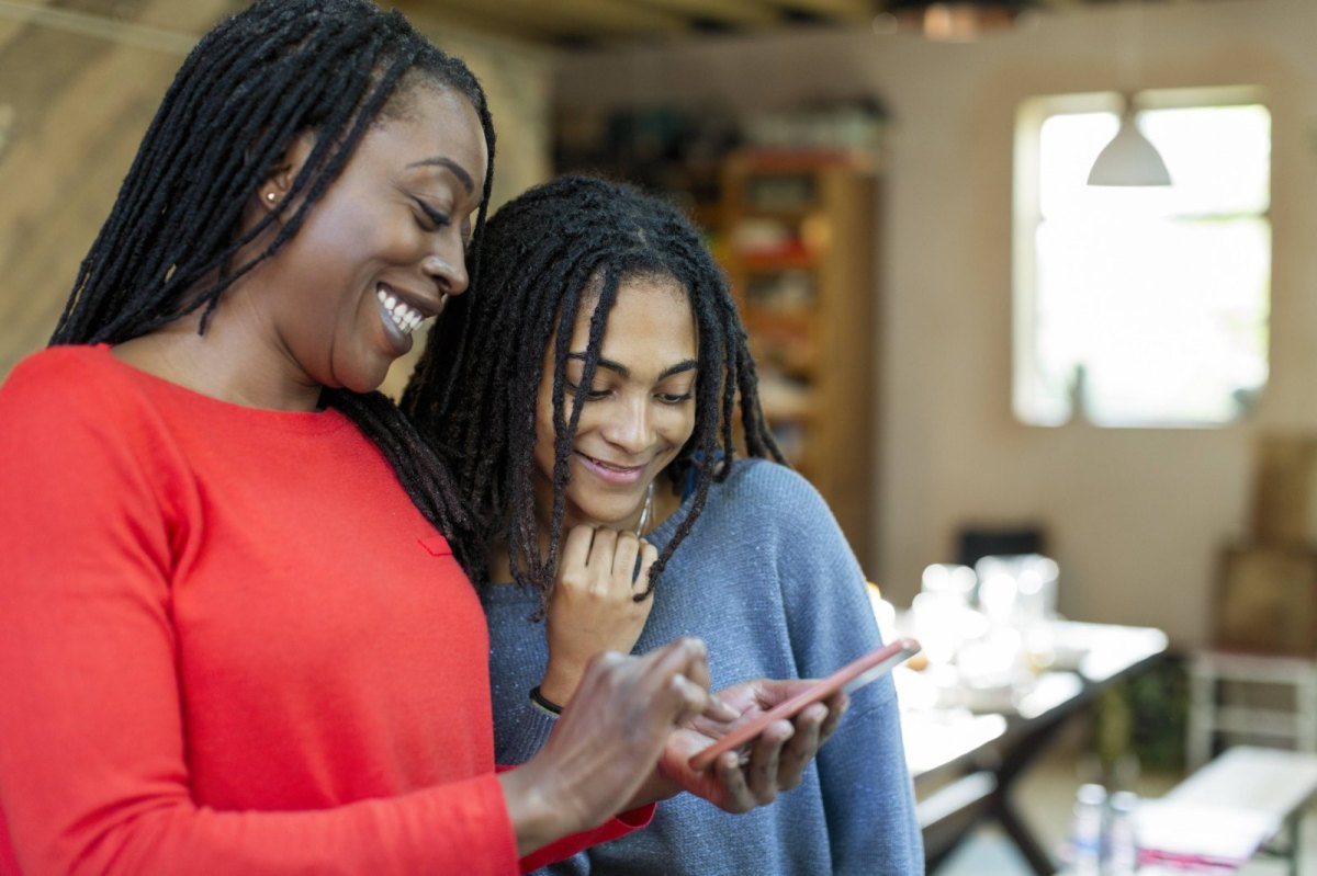 Zwei lachende Frauen schauen ein Video auf ihrem Smartphone.