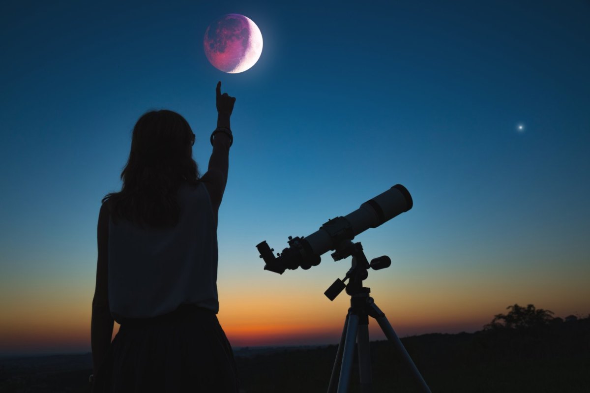 Frau mit Teleskop zeigt auf den Mond.
