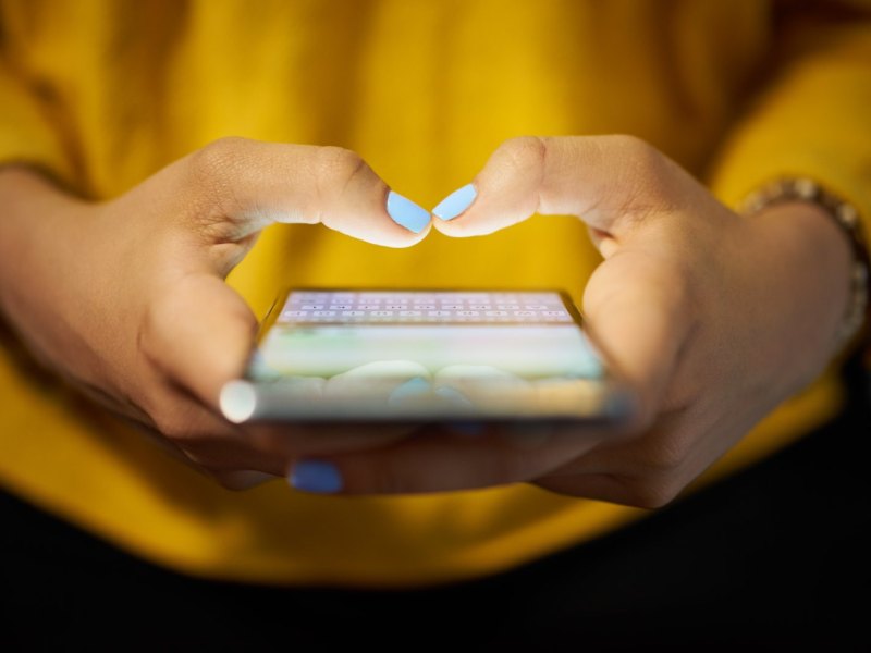 Frau tippt eine Nachricht auf ihrem iPhone.