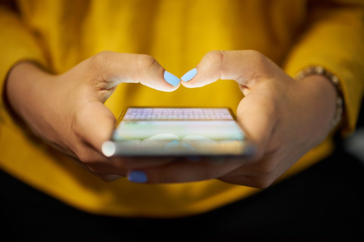 Frau tippt eine Nachricht auf ihrem iPhone.