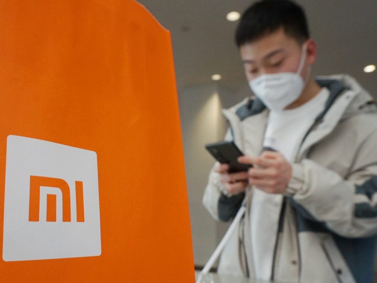 Mann mit Handy und Xiaomi-Logo.