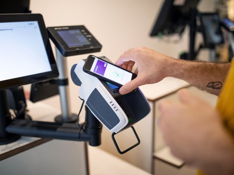 Person zahlt kontaktlos mit dem Handy