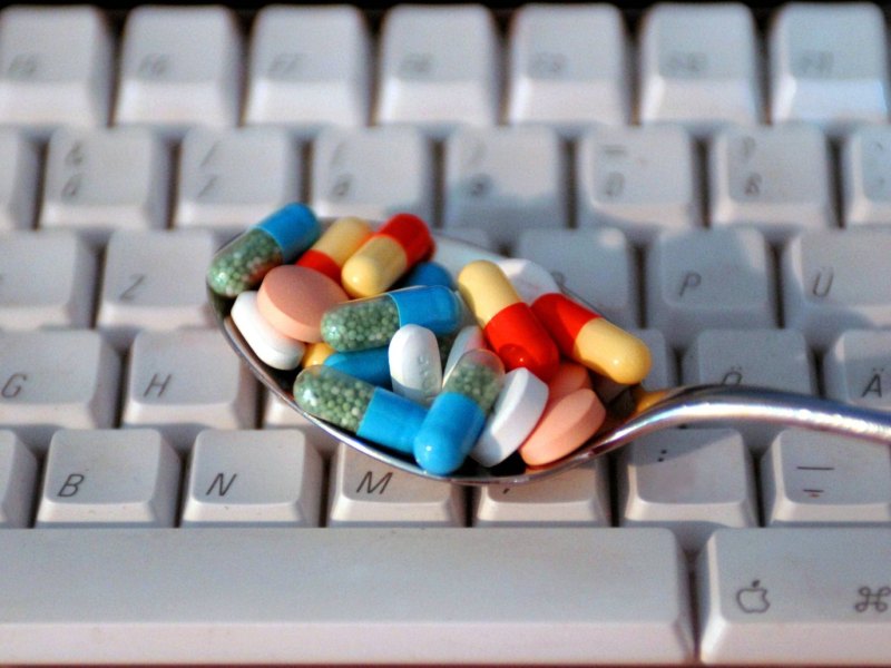 Löffel mit Pillen auf einer Tastatur