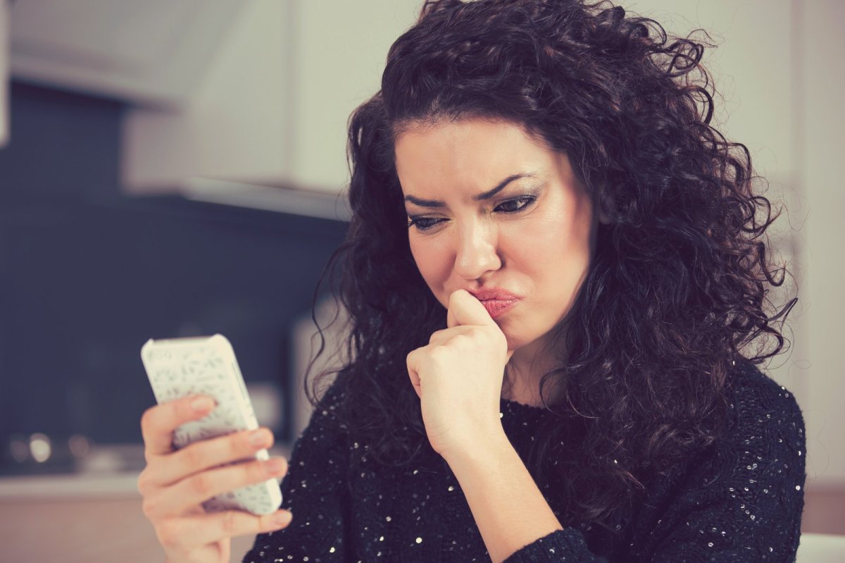 Frau blickt skeptisch auf ihr Handy.