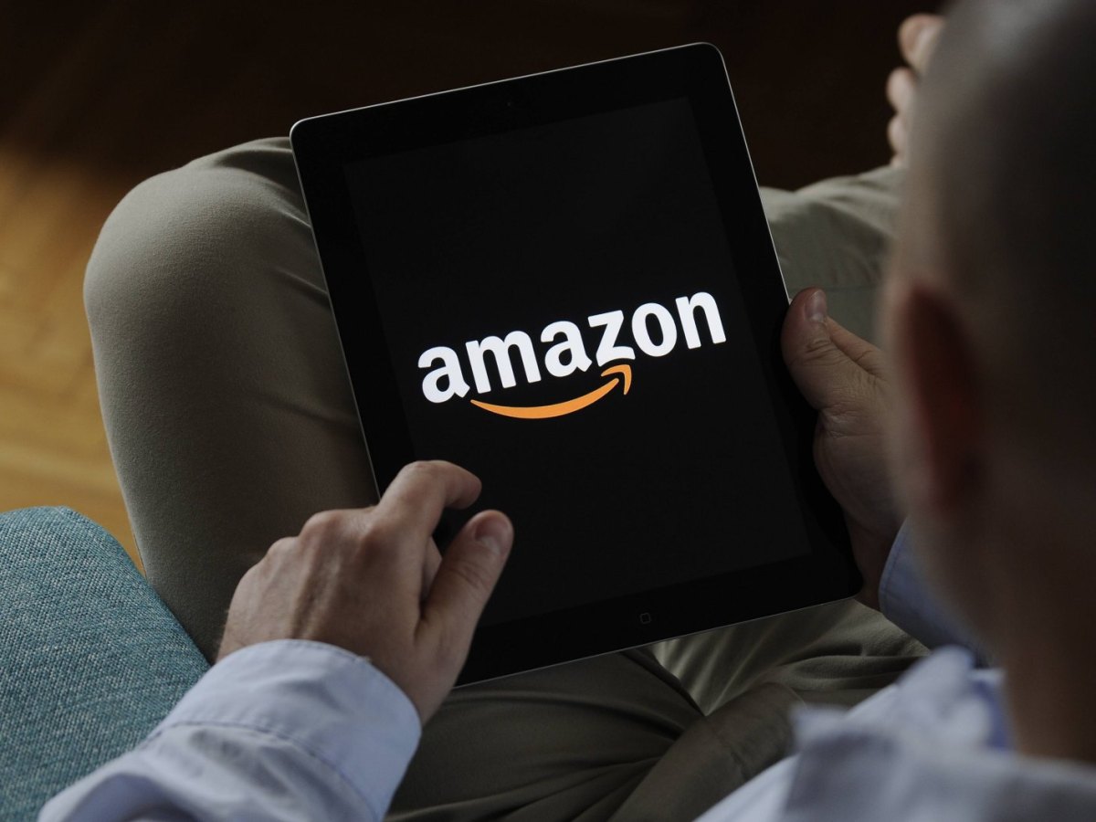 Ein Mann mit einem iPad in der Hand. Auf dem iPad ist das Amazon-Logo zu sehen.