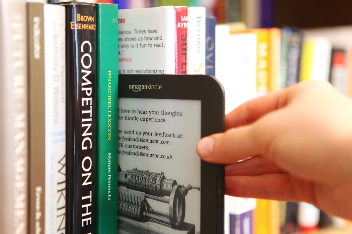 eBook-Reader Kindle von Amazon wird aus Bücherregal gezogen